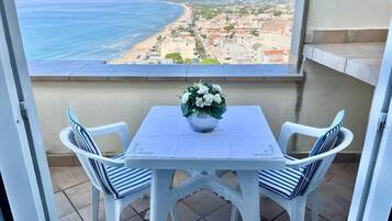 Un balcó amb taula i cadires, amb vista a una platja i al skyline de la ciutat.