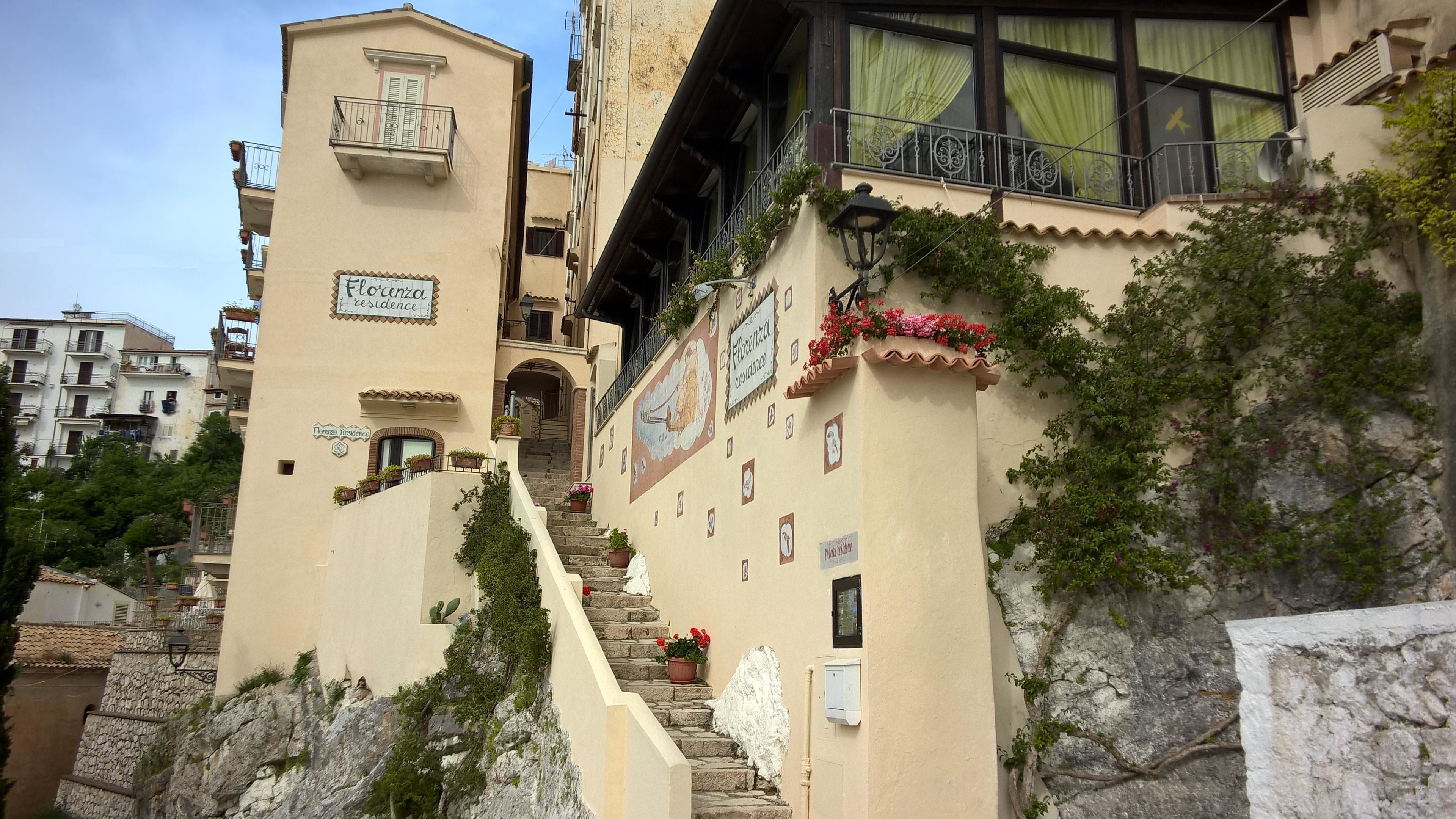 Ein Gebäude mit mehreren Balkonen und einer Treppe, mit Schildern, die 'Florenz Residence' anzeigen.