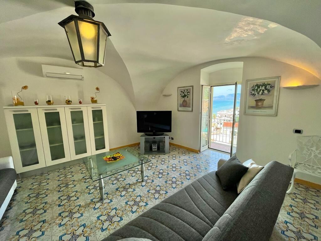 Una sala de estar con un sofá, una televisión, un mueble y un piso estampado.