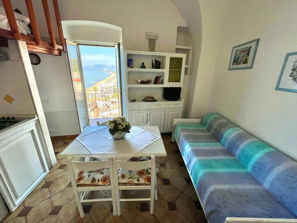 Un espacio habitable compacto con una mesa de comedor, un sofá y vista al mar.