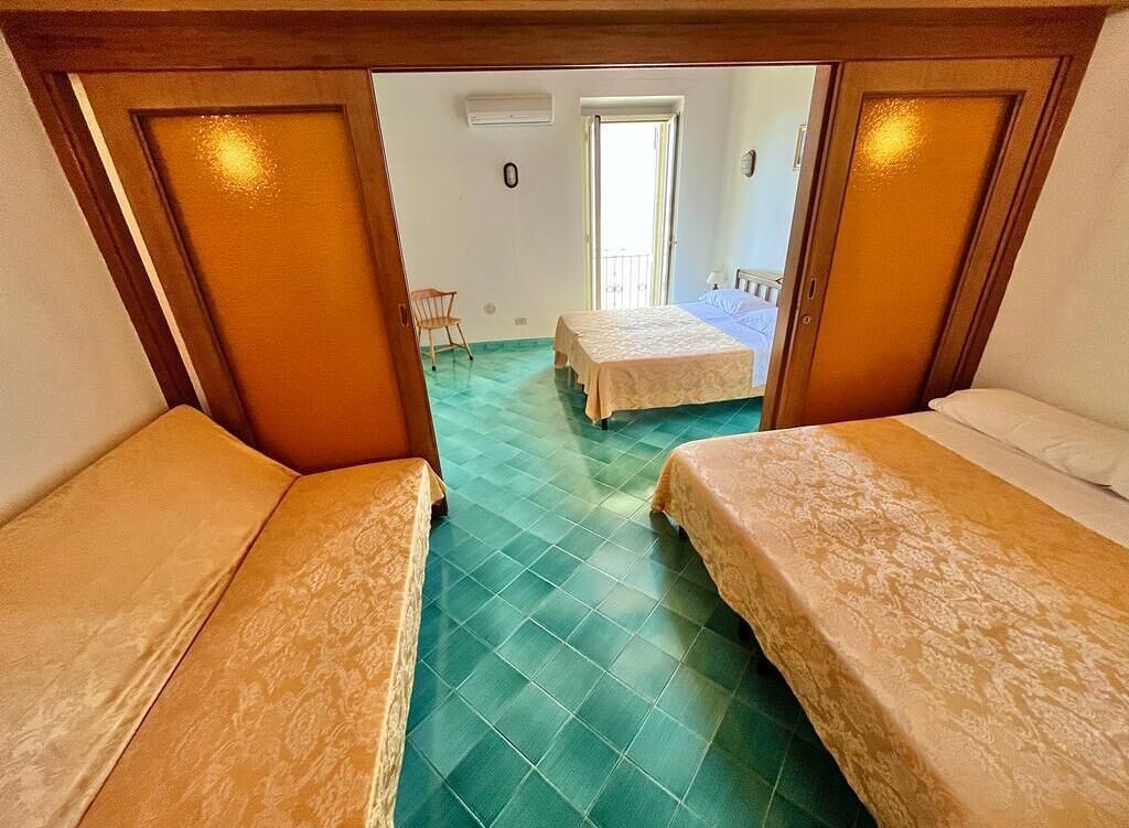 A room with two beds, a wooden ceiling, and a green floor.