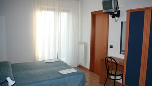 Une petite pièce simple, avec un lit, une chaise, un téléviseur fixé au mur et une armoire.