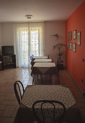A dining area with four tables, a television, and a potted plant. - B&B Villa Ruberto (San Giovanni Rotondo)