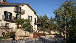 Un immeuble de deux étages avec une façade en pierre, de nombreux balcons et un escalier en pierre menant à l’entrée.