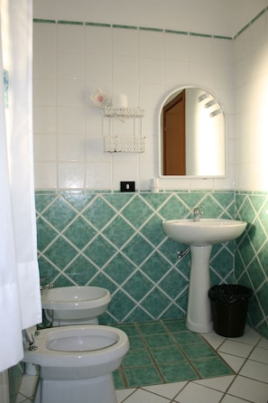A bathroom with two sinks, a toilet, a mirror, and a trash bin. - B&B Villa Ruberto (San Giovanni Rotondo)