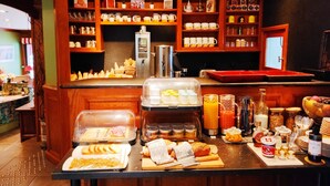 En morgenmadsbuffet med et udvalg af mad, en kaffemaskine og forskellige drikkevarer.