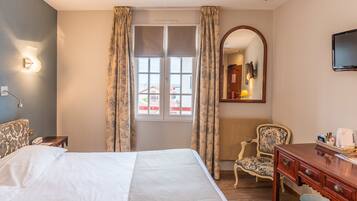 Ein Hotelzimmer mit einem Bett, einem Schreibtisch, einem Stuhl, einem Spiegel und einem fenster mit Vorhängen.