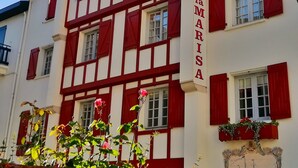 Et hotel med en traditionel facade, flere vinduer med røde markiser, og et tydeligt skilt med teksten "HOTEL la MARISA".