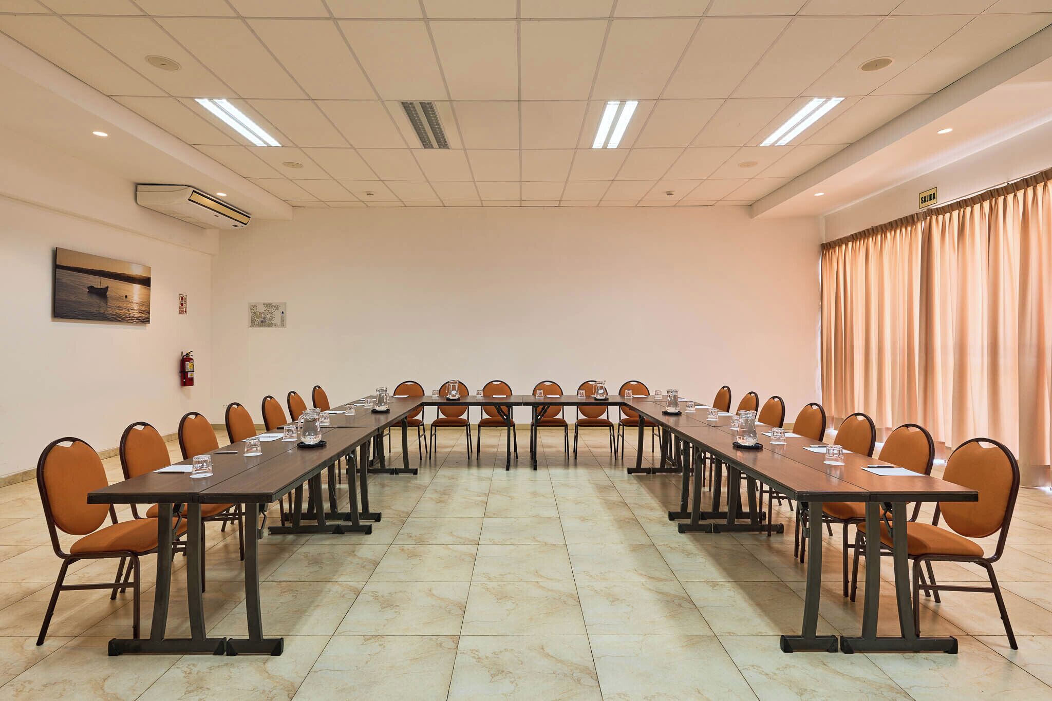 A conference room with a long table, chairs, and a fire extinguisher on the wall.