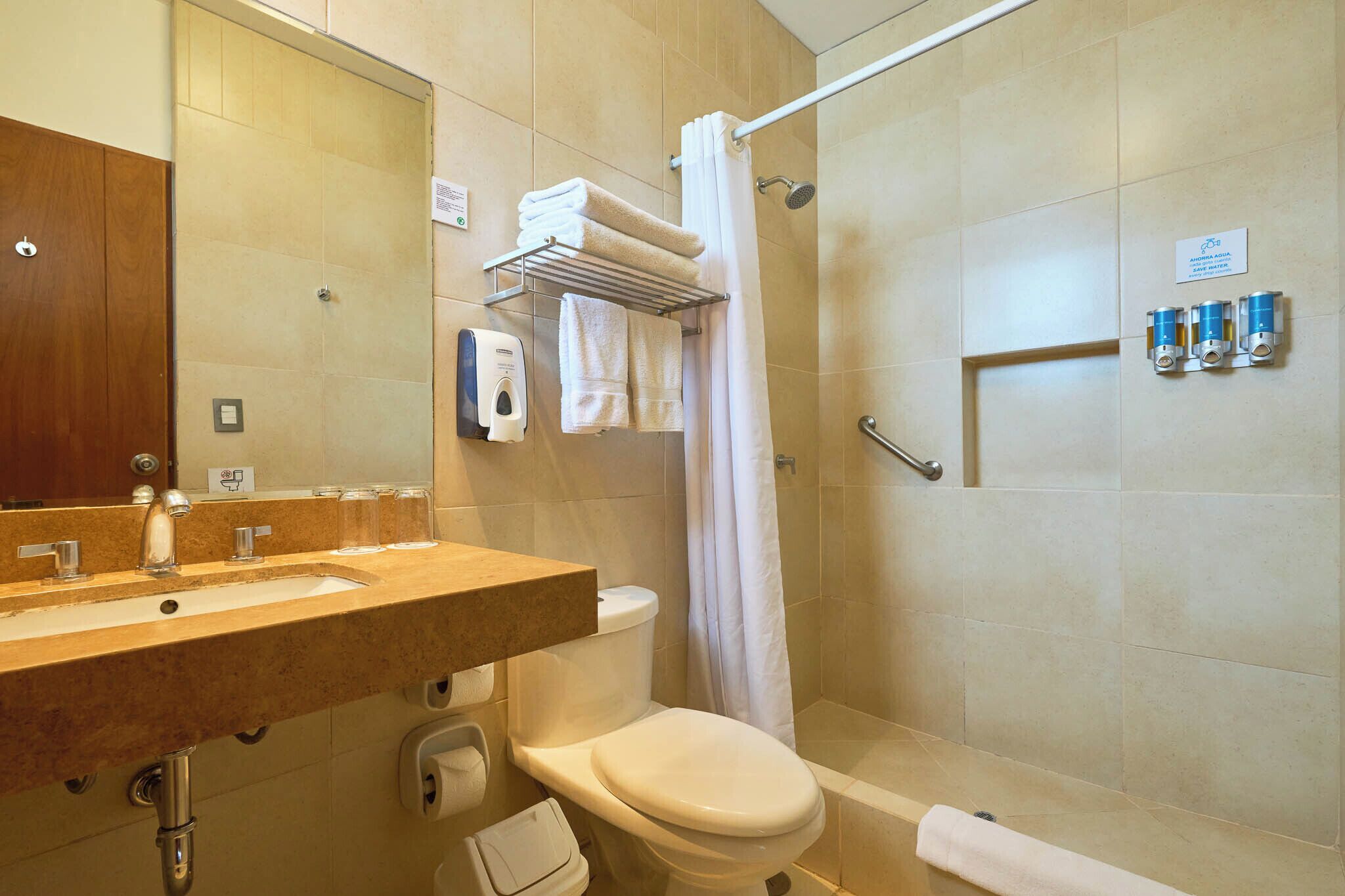 A bathroom with a sink, toilet, and shower. There are towels and toiletries on the wall.