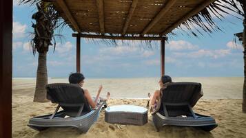 En la playa, camastros, masajes en la playa y vóleibol de playa