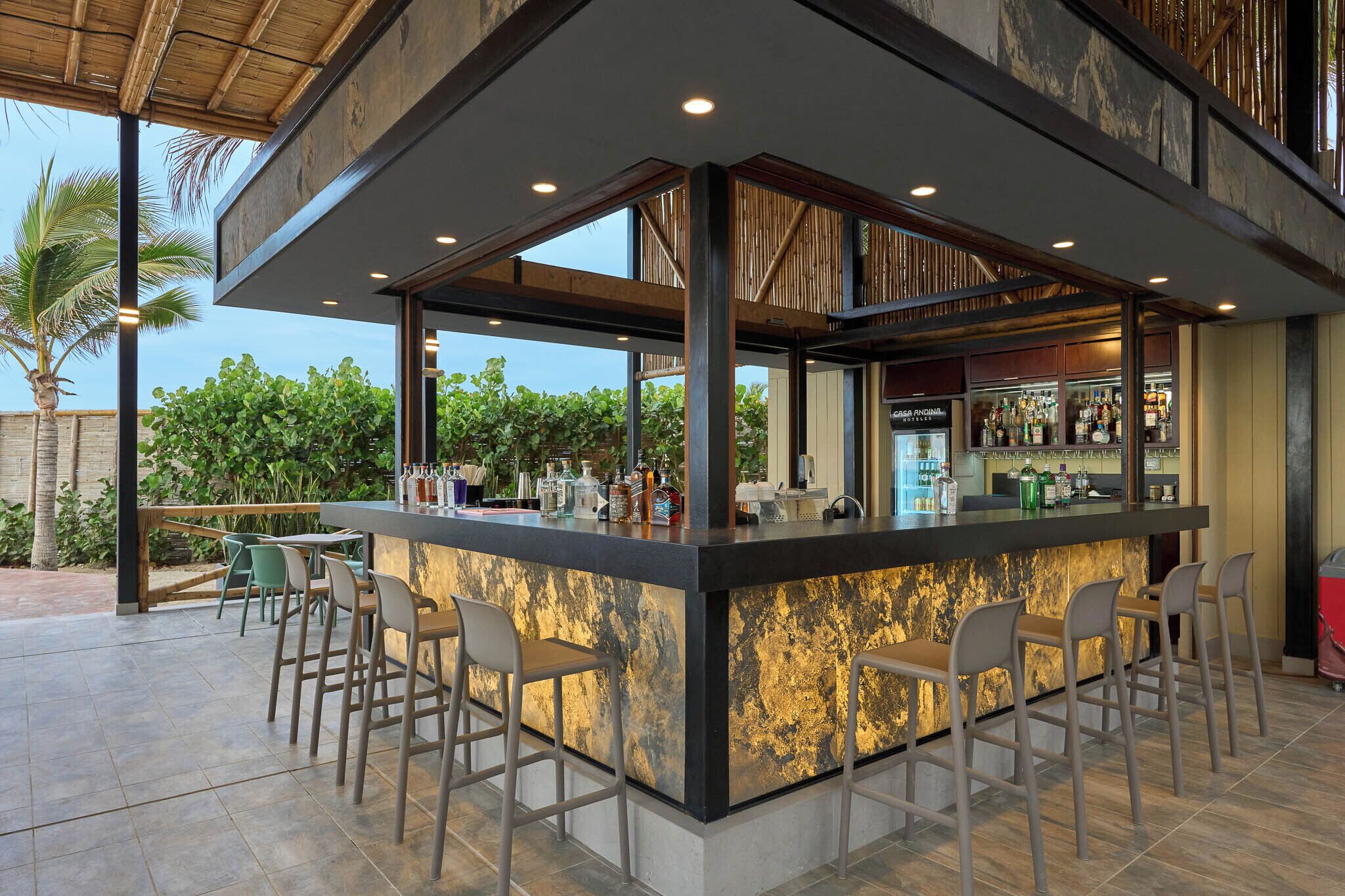 Eine moderne Außenbar mit Bar, Sitzgelegenheiten und Blick auf Grünflächen.