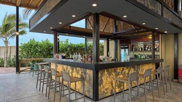 Eine moderne Außenbar mit Bar, Sitzgelegenheiten und Blick auf Grünflächen.
