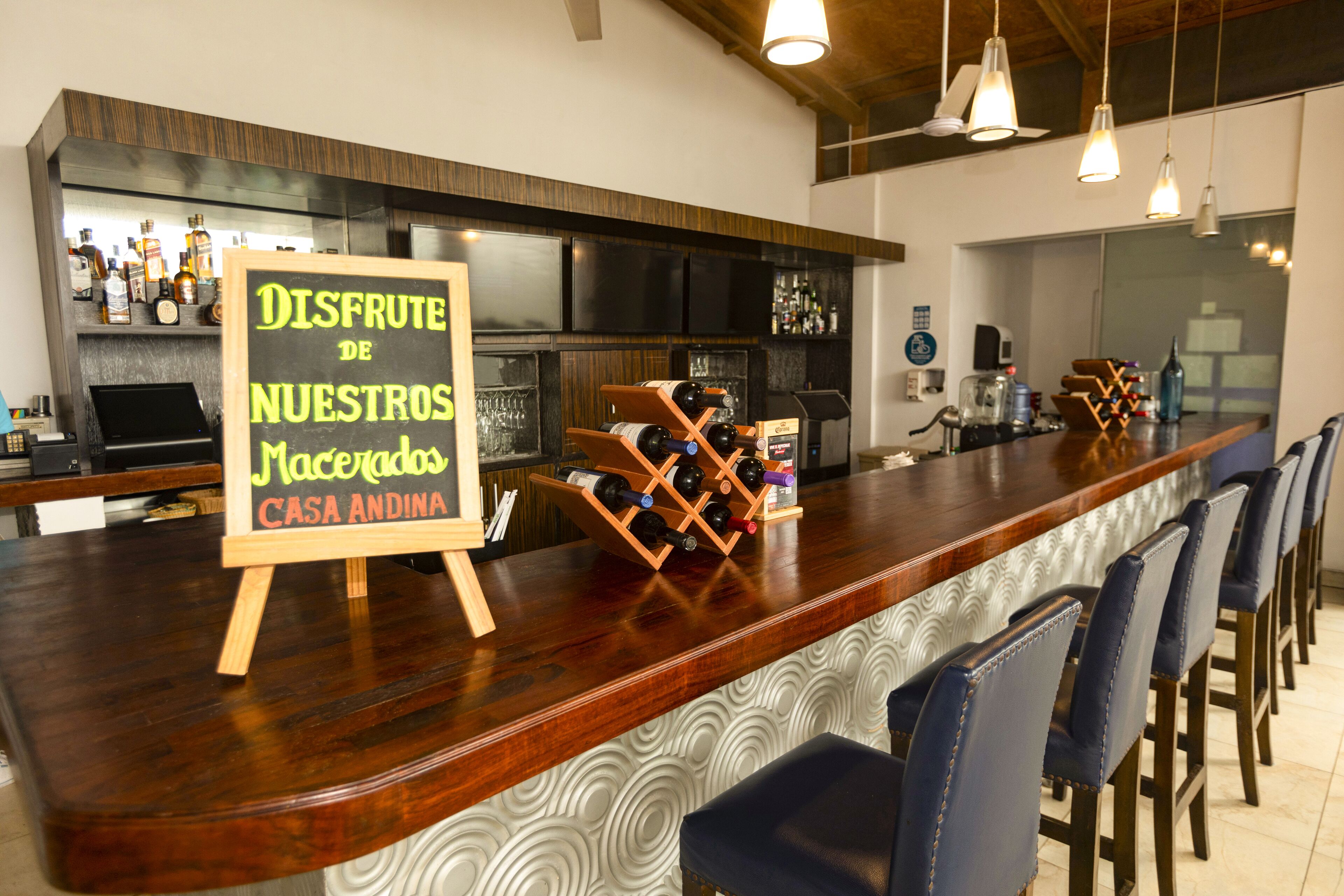 Un espace bar avec un comptoir en bois, des étagères à vin et des tabourets de bar.