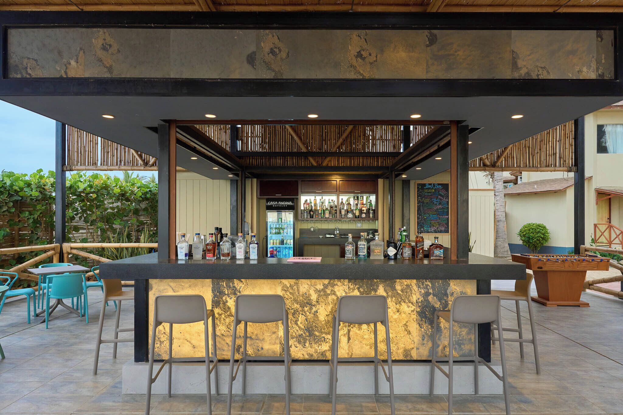 Zona de bar con mostrador, taburetes y una mesa de futbolín.