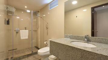 Un baño moderno con ducha envuelta en vidrio, inodoro e lavamanos sobre encimera de granito.