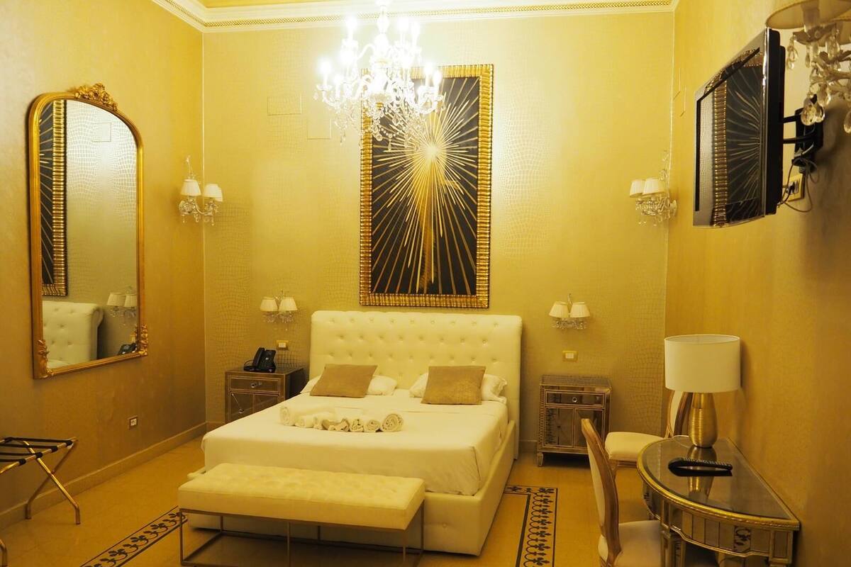 Ein luxuriöses Schlafzimmer mit einem großen Bett, einem Schminktisch mit Spiegel, einer Kristallleuchtre und einem Fernseher.