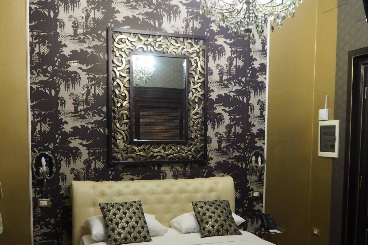 Ein Hotelzimmer mit einem großen Bett, einer Kristalllüster und einem Wandspiegel.