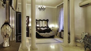 A spacious room with a large bed, a chandelier, and a chair. - Contessa Arrivabene Antica Dimora (Rome)