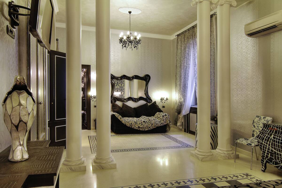 Ein geräumiger Raum mit einem großen Bett, einer Chandelierleuchtre und einem Sessel.