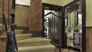 A grand staircase with a statue, a mirrored cabinet, and a checkered floor. - Contessa Arrivabene Antica Dimora (Rome)