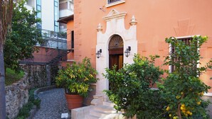 A courtyard with a stone pathway, a reception sign, a potted plant, and a building with an arched entrance. - Contessa Arrivabene Antica Dimora (Rome)