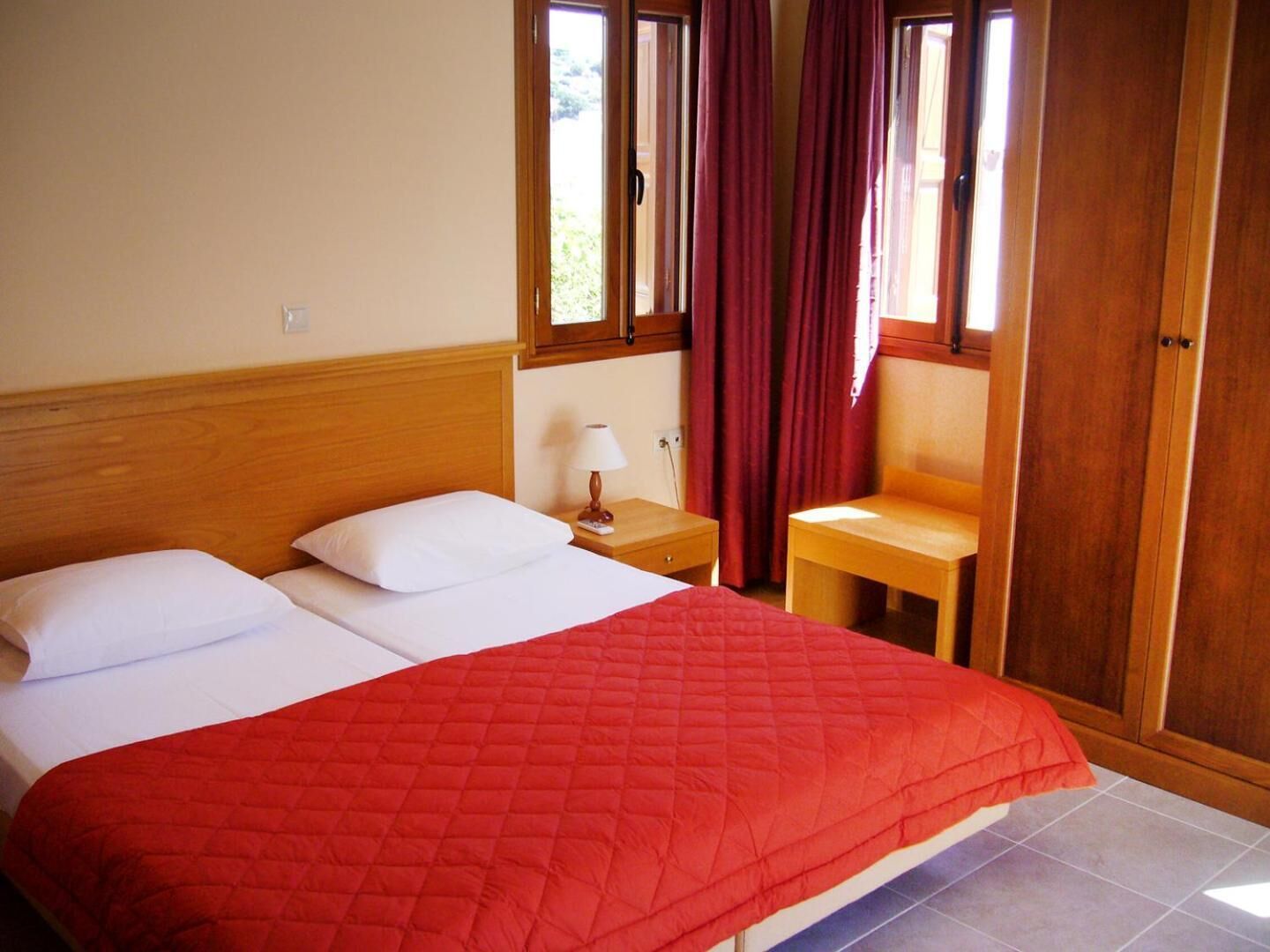 A hotel room with a bed, a nightstand, a chair, and a wardrobe.