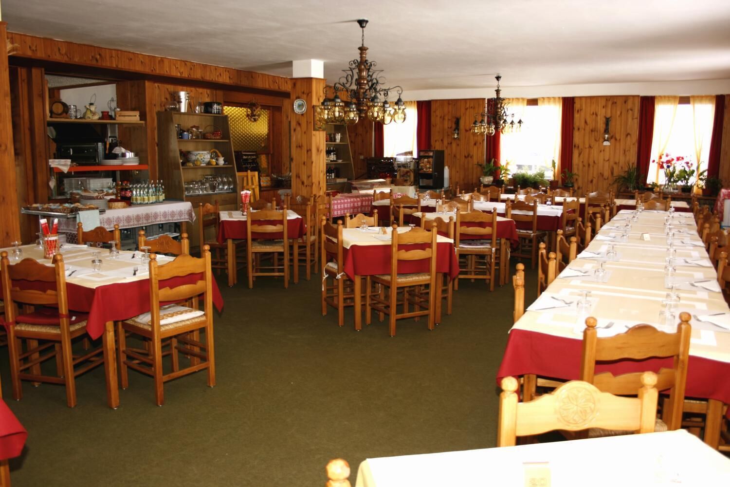 A restaurant with wooden walls, multiple tables set for dining, and a chandelier.