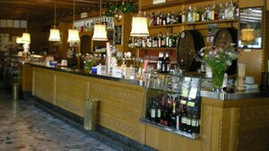Zona de bar con suelo de mármol, mostrador de madera y diferentes botellas y vasos.