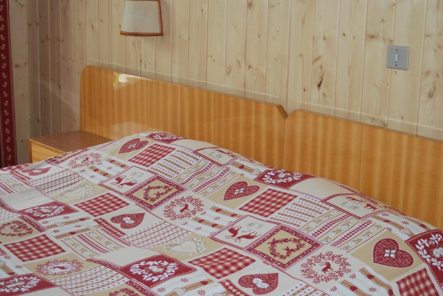 A wooden bunk bed with a quilted bedspread featuring geometric and floral patterns.