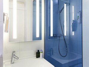 A modern bathroom with a glass-enclosed shower, a white sink, and a mirror with built-in lighting. - ibis Styles Toulouse Nord Sesquières (Toulouse)