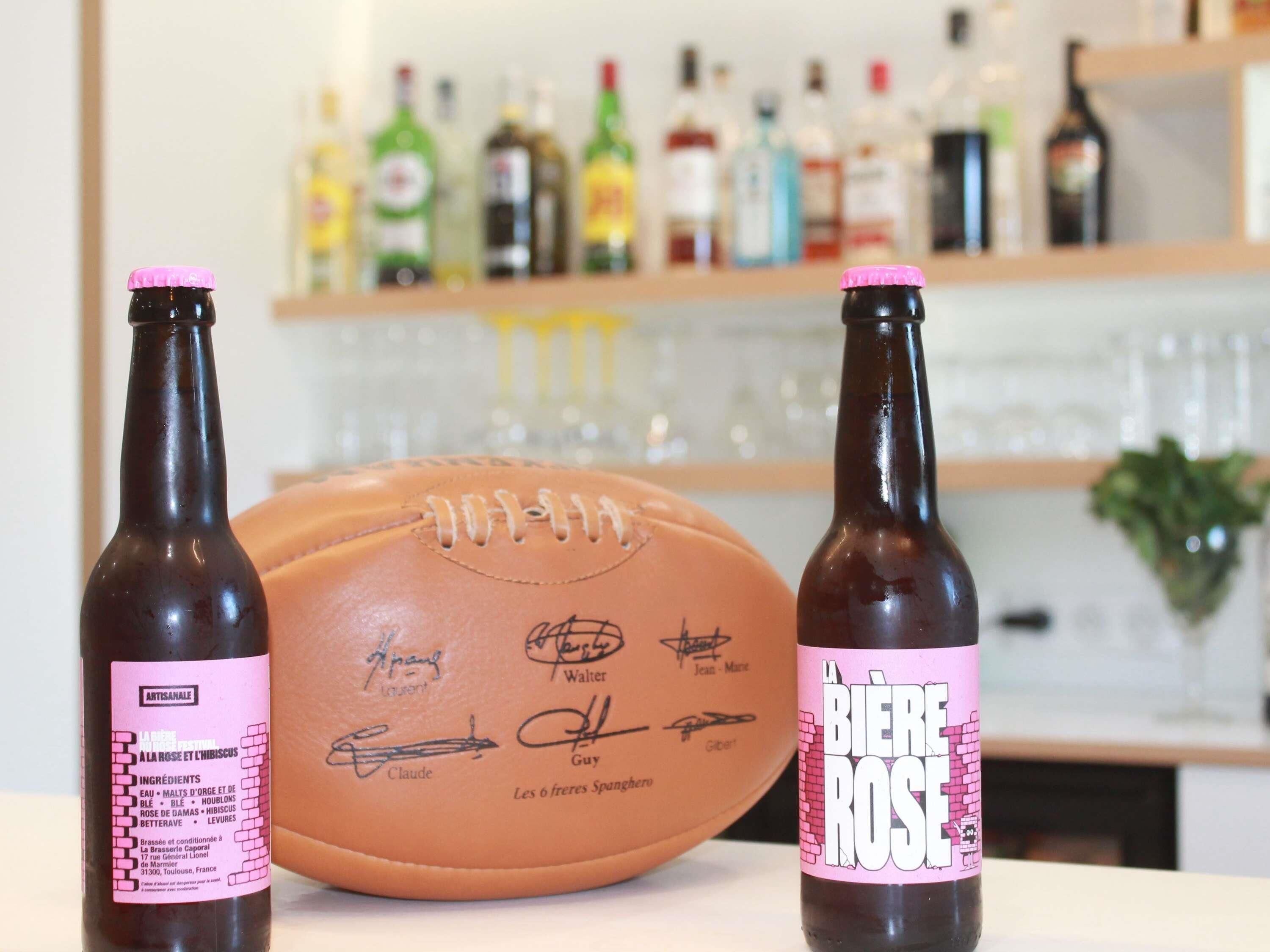 Two bottles of beer with pink labels and a signed football in the foreground.