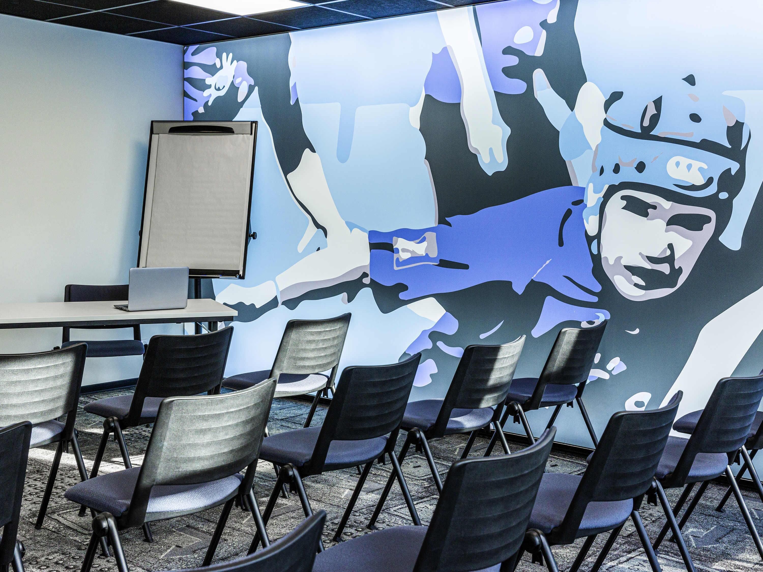 Een vergaderruimte met een whiteboard, een laptop en opklapbare stoelen.