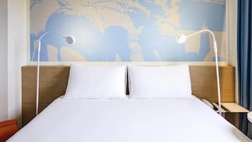Quarto de hotel com uma cama grande, duas mesas de cabeceira e um mural de um mapa-múndi na parede.
