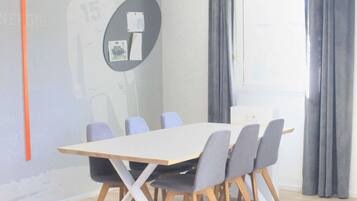Uma sala de conferências com uma mesa comprida, seis cadeiras e uma tela de projetor.