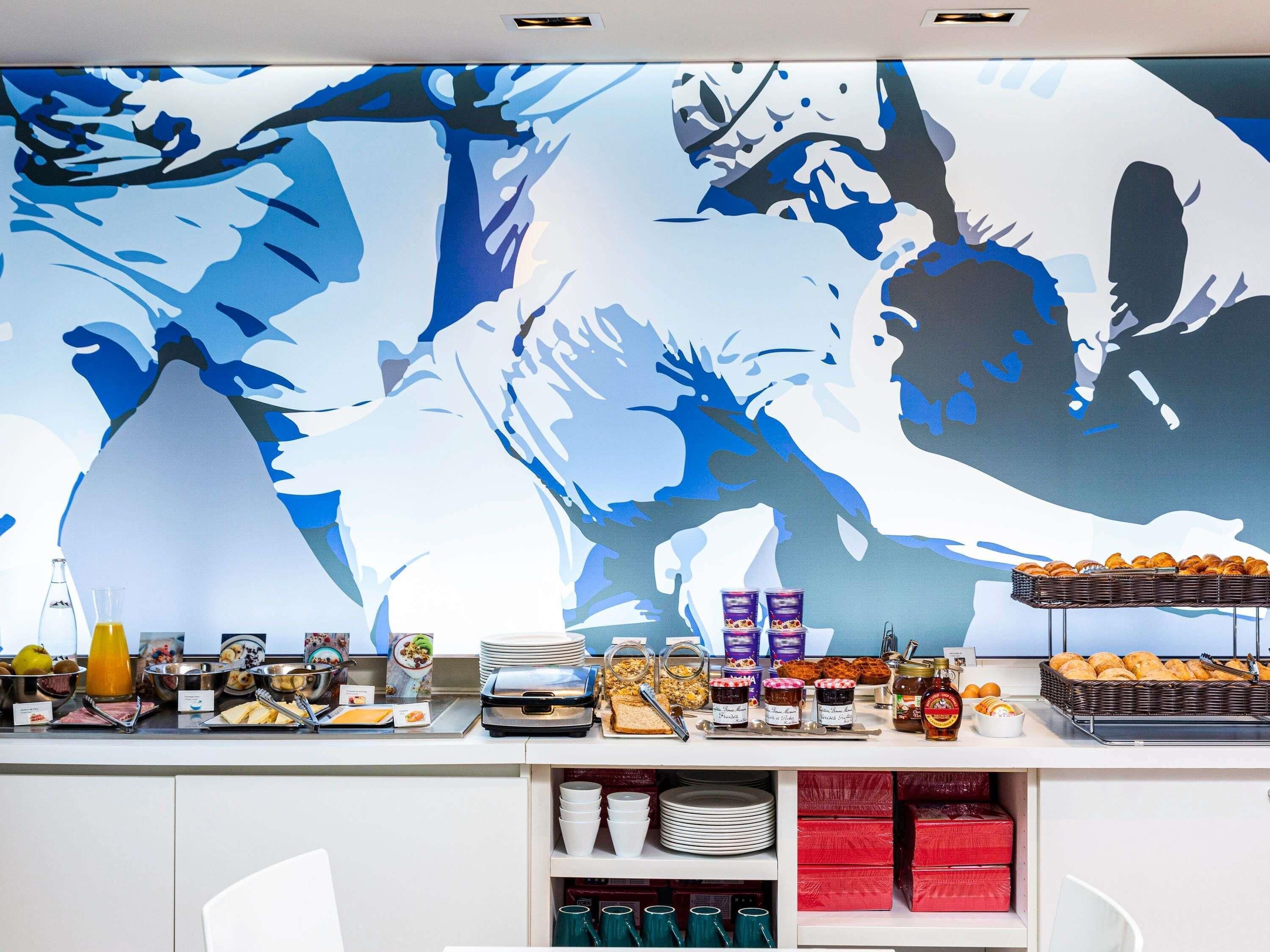 A breakfast buffet with various food items and a large abstract painting on the wall.