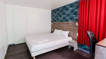 Una habitación de hotel con cama, escritorio, silla y cortina roja.