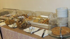 A buffet table with various food items, including pastries and bread, covered with glass domes and trays.