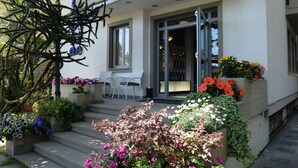 A two-story building with a balcony, outdoor seating, and flower planters.