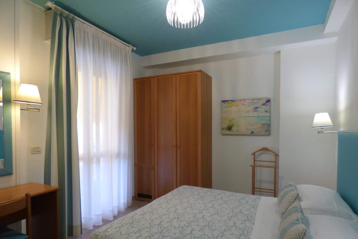 Une chambre à coucher avec un lit, un bureau, une armoire et un tableau au mur.