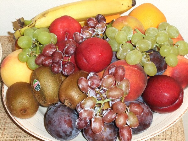 Un plato con una variedad de frutas, como plátanos, kiwis, uvas, melocotones y ciruelas.
