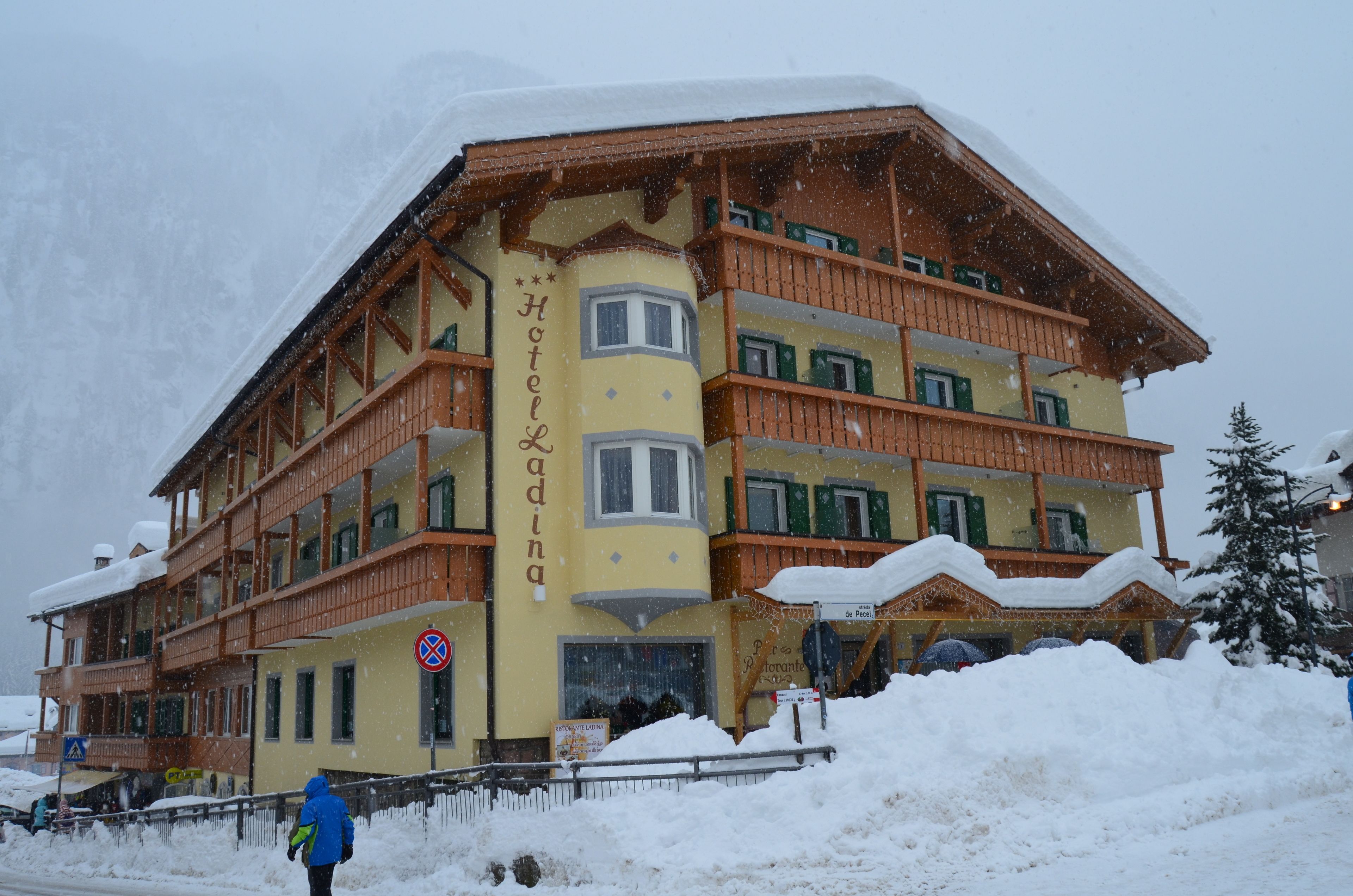 A multi-story hotel with a traditional Alpine architectural style, featuring balconies and a snow-covered roof.