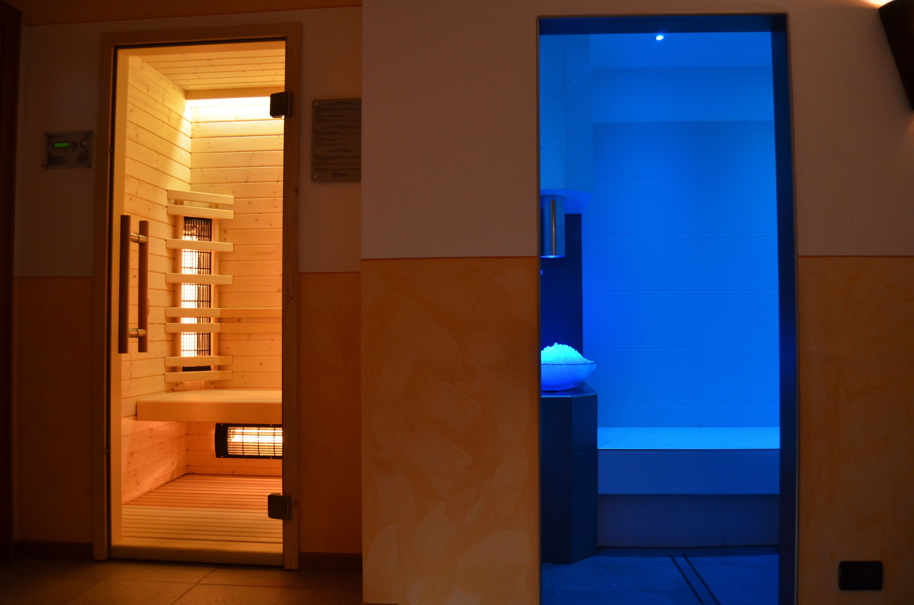 A sauna with wooden benches and a blue-lit room.