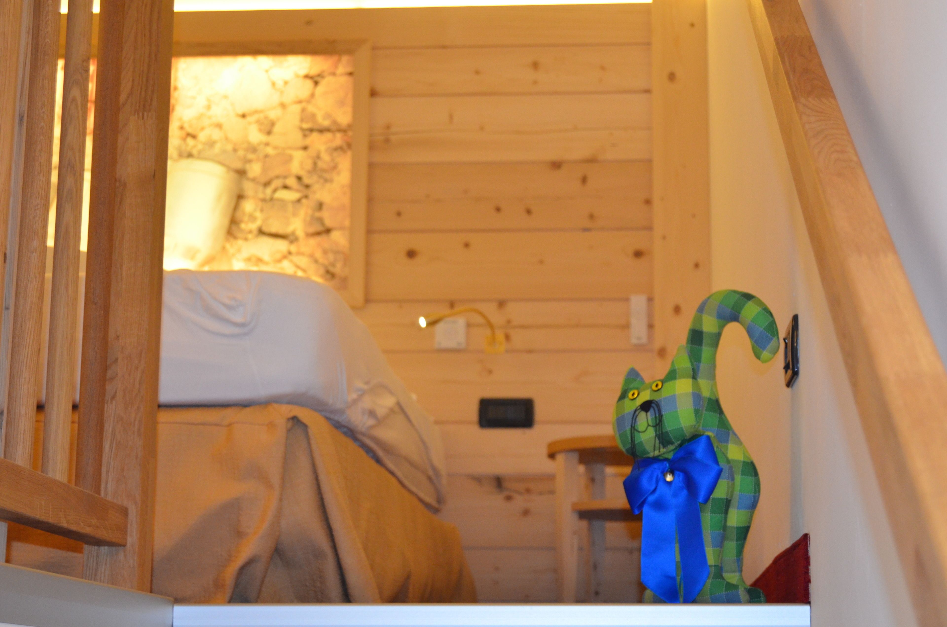 Un interior de madera con una cama, una pared de piedra y una decoración a cuadros verdes y amarillos.