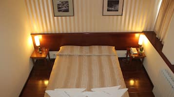 Una habitación de hotel con una cama grande, dos mesitas de noche con lámparas y cuadros en la pared.