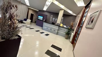 Welcome to our reception area, featuring a central desk, comfortable seating, and a lush potted plant.