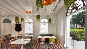 A dining area with white tables, green chairs, and hanging plants. - Macalister Mansion (George Town)