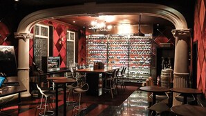A bar area with a wine rack, bar stools, and a laptop on a table. - Macalister Mansion (George Town)