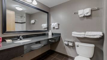 Un baño moderno con un espejo grande, un lavamanos, un inodoro y toallas colgadas en la pared.