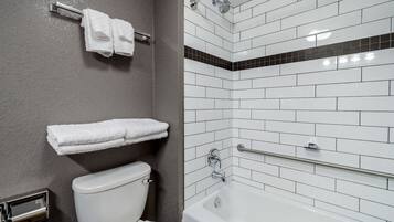 A bathroom with a white toilet, a bathtub, and a towel rack with two towels.